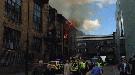 Six fire appliances are at the scene, with firefighters seen pouring water on the building from a high ladder as flames blew windows out.